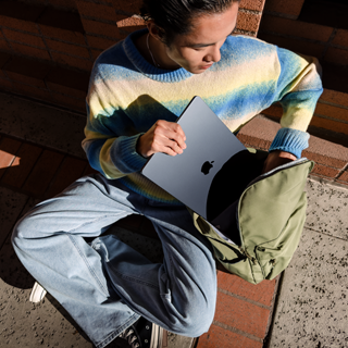 En person som legger en lukket 15-tommers MacBook Air ned i en sekk