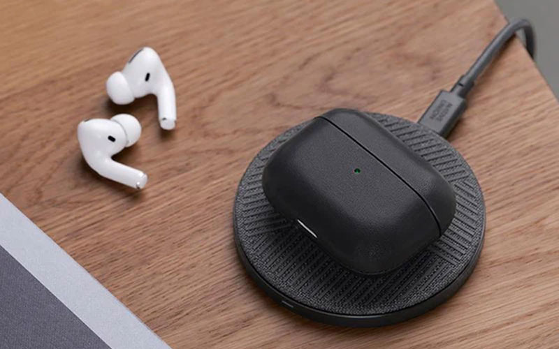 Apple Airpods case on a charger with the headphones plugs next to it