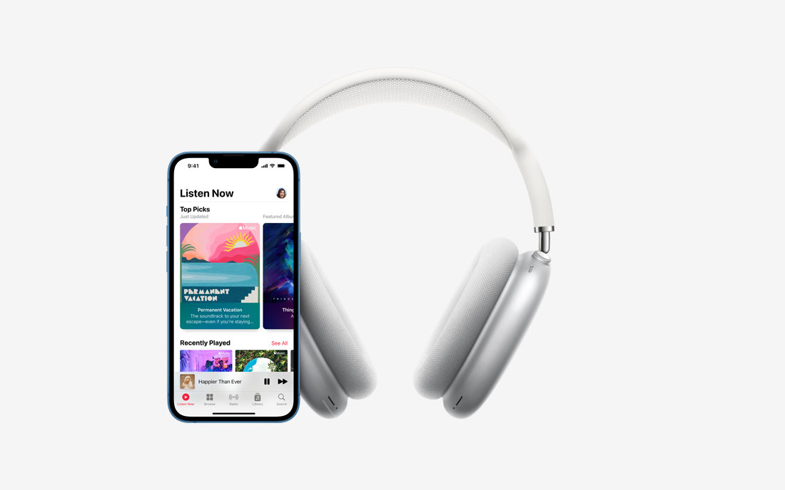 Apple grey headphones next to Apple iPhone with music app open