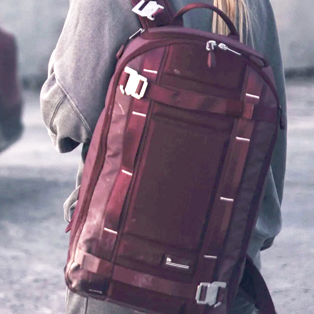 Red Db backpack on back of blonde girl with grey background