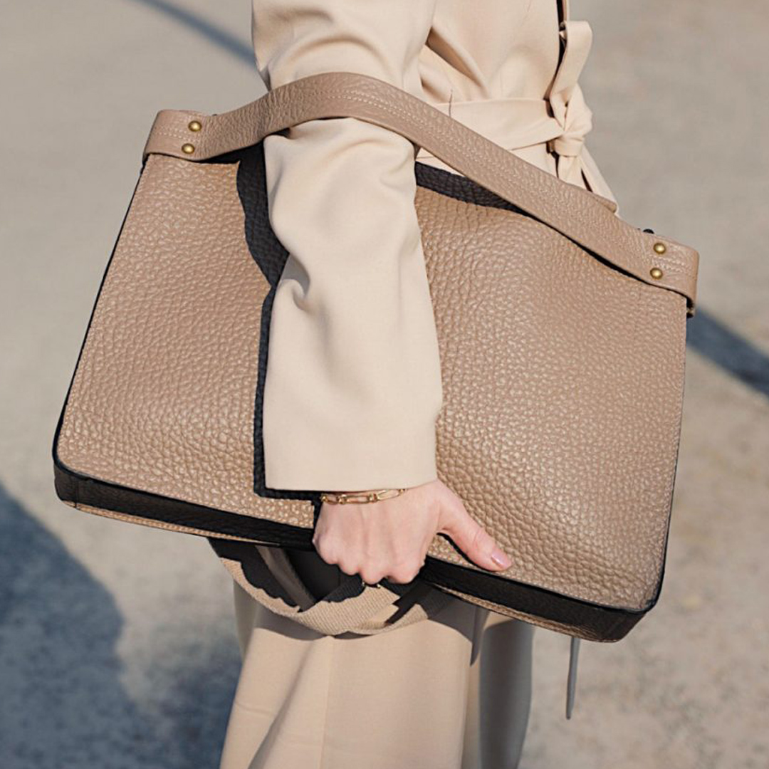 Beige leather carrier held in one arm