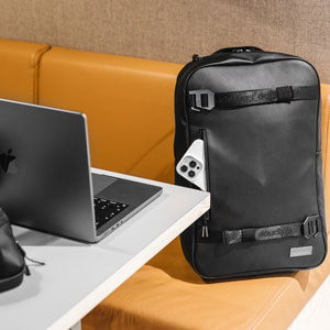 MacBook Pro on a table with black backpack next to a sofa on the floor