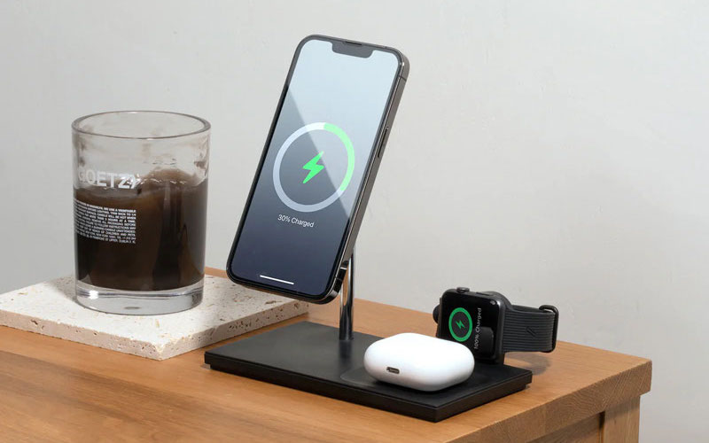 Apple iPhone, Apple Watch and AirPods on a charger on a nightstand