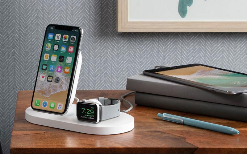 Apple iPhone and Apple Watch on a wireless stand on a night table
